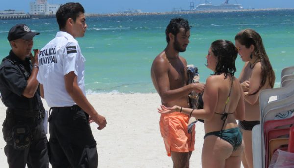 Progreso police instruct two Spanish women to put their tops back on. (PHOTO: Megamedia/GABINO TZEC VALLE)