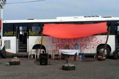 A stolen bus blocks a highway in Oaxaca. The sign reads "Freedom for political prisoners." (PHOTO: mexiconewsdaily.com)