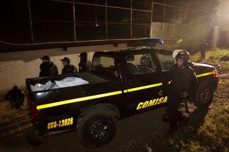 Guatemalan officers place the body of a guard killed in prison riot in the bed of a pickup truck. (PHOTO: uk.news.yahoo.com)
