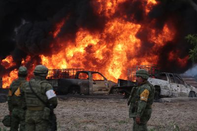 Soldiers stand in front of the flames generated by a fire in a clandestine fuel valve May 7. Photo: Jose Castanares/AFP via Getty Images