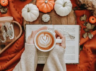 anonymous woman with coffee near pumpkins